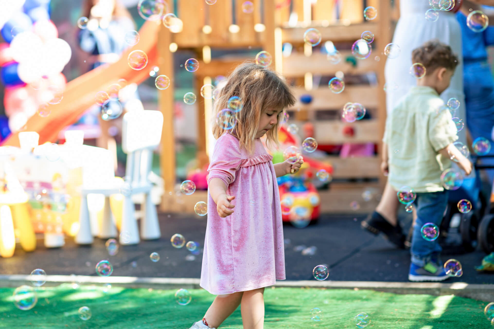 Copil bucurându-se de baloane de săpun la un eveniment festiv.